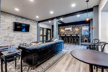 A modern living room with a black leather sofa and a flat screen tv mounted on a brick wall.